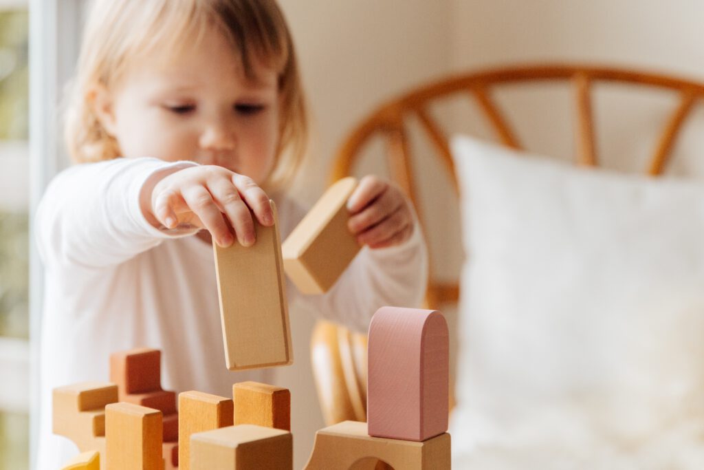 Ein kleines Kind spielt mit Holzbausteinen. Foto von Tatiana Syrikova von Pexels